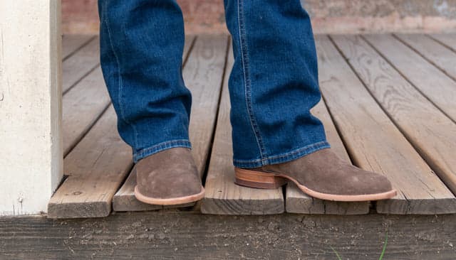 man in jeans and boots on a porch
